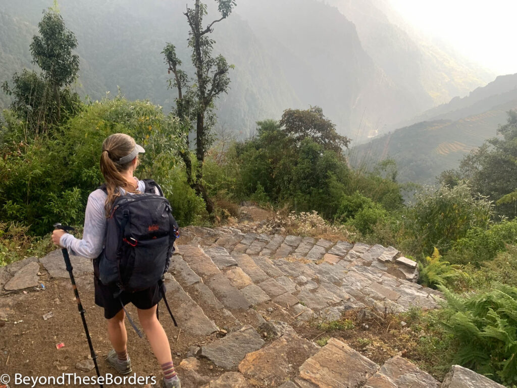 I'm heading down neatly laid stone stairs with my hiking poles and pack.