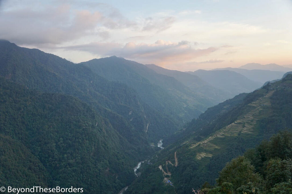 Sunset view of the valley we just hiked from.  River visible far below between the green hills. 