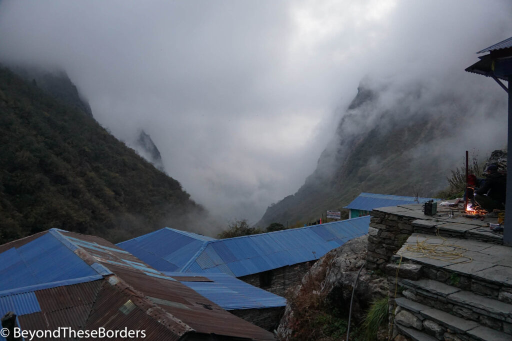 Early night view from our lodge in Derail.  Blue rooftops of other lodges just below us.  High mountains belong and the fog filled valley between them.