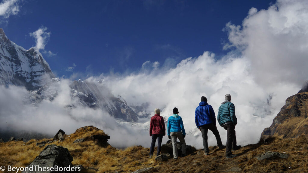 3 of my friends and I staring at the giant mountains with thick clouds covering the right half of the range.