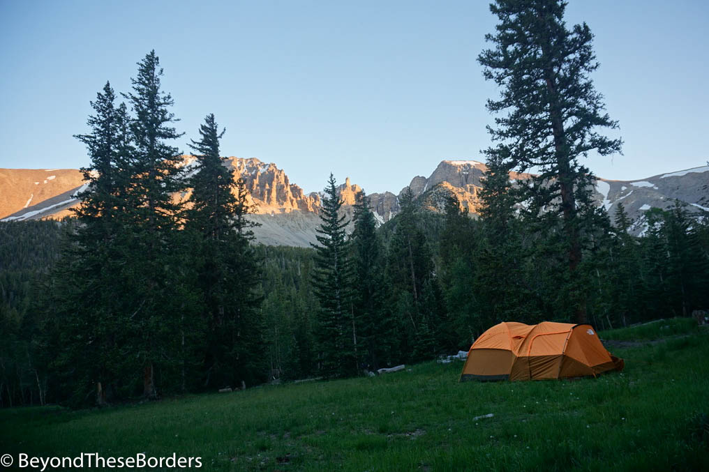 Tent set up in the meadow of Wheeler Peak Campground.  Pine trees and mountains in the background.