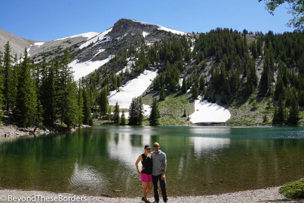 Myself and my partner standing in front of Stella Lake with the snowy mountain behind it.