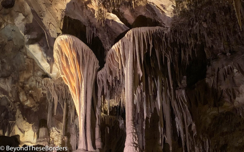 Structures inside the cave that look like feet with sticky gum stretching below them to the ground